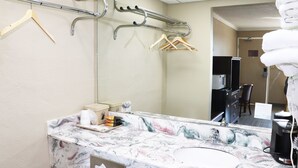 A bathroom with a marble countertop, a sink, a mirror, a towel rack, and a shower area. - Super 8 by Wyndham Clarksville East (Clarksville)