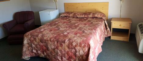 Une chambre d’hôtel avec un lit, une chaise, un bureau, une lampe et un tableau au mur.