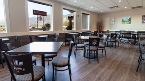 A spacious restaurant with multiple tables and chairs, large windows offering a view of mountains, and a sign for 'Kanata' on the window. - The Kanata by BCMInns Invermere (Invermere)