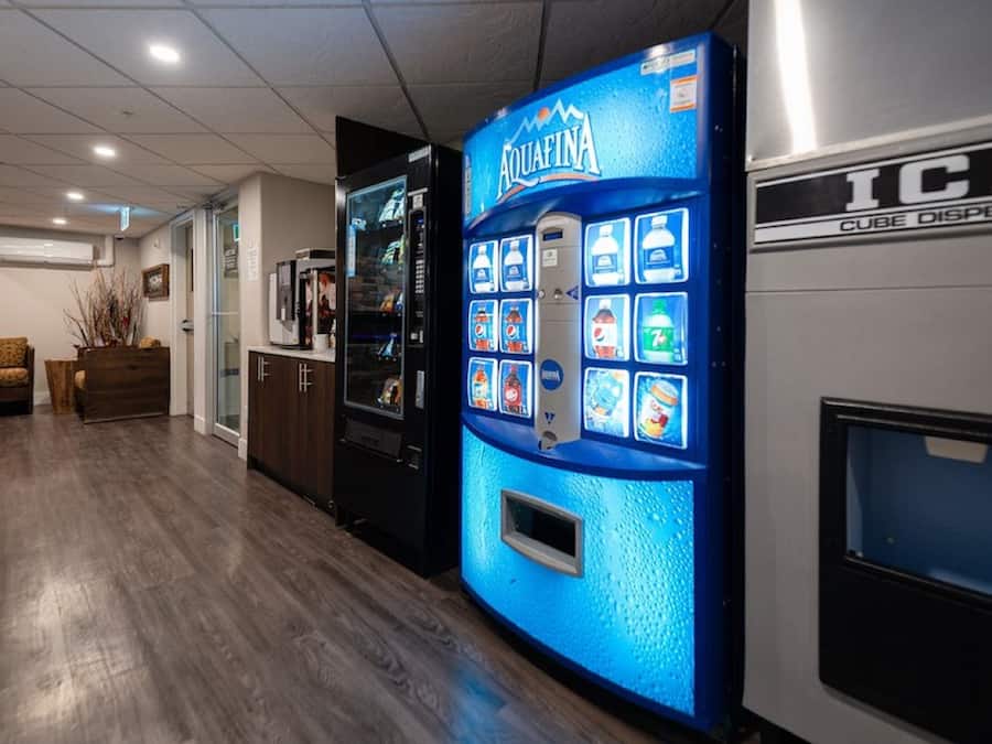 Un pasillo con una máquina expendedora que dice 'Aquafina' y un dispensador de hielo.