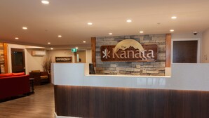 A reception area with a stone wall and a wooden reception desk. - The Kanata by BCMInns Invermere (Invermere)