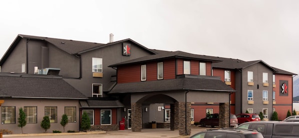 A multi-story hotel with a modern design, featuring a prominent red and grey color scheme, stone accents, and a covered entrance.