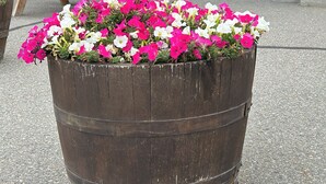 A building with stone walls, a wooden picnic table, and a flower planter. - The Kanata by BCMInns Invermere (Invermere)