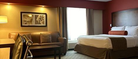 Una habitación de hotel con cama, sofá, escritorio y una silla.