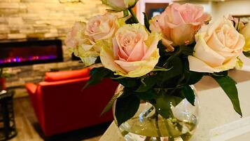 Un vaso con rose rosa su un ripiano in una stanza con una parete in pietra e un divano rosso.