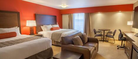 Een hotelkamer met twee bedden, een slaapbank, een bureau en een stoel.