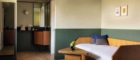 Quarto moderno com cama de madeira, uma mesinha e um espelho.