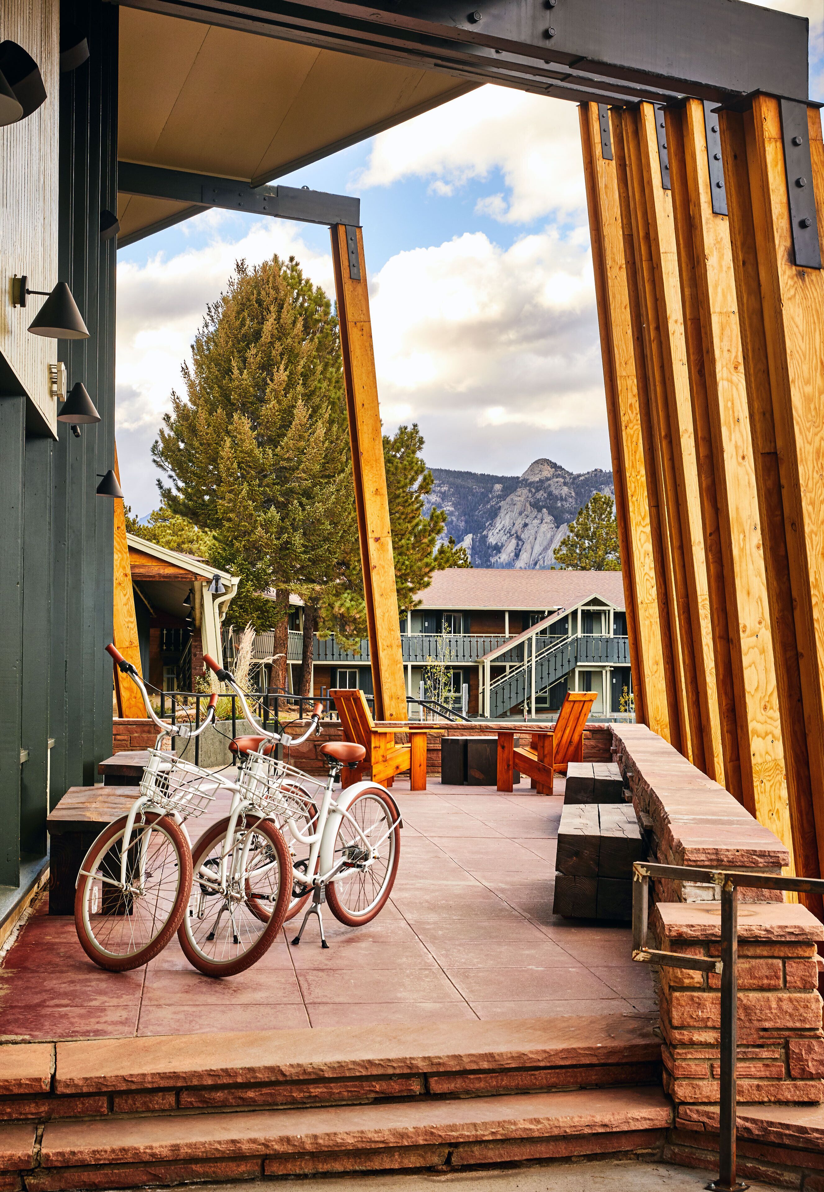A wooden deck with a bicycle, outdoor seating, and a view of mountains.
