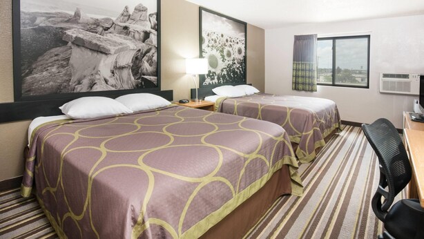 A hotel room with two beds, a desk, a chair, a lamp, and a large framed picture on the wall. - Super 8 by Wyndham Jamestown (Jamestown)