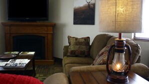 A living room with a fireplace, a television, a table with magazines, and a lamp. - Super 8 by Wyndham Jamestown (Jamestown)
