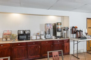 A kitchenette with a microwave, toaster, coffee maker, and coffee dispenser.