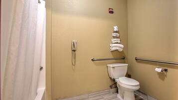 A bathroom with a toilet, a hand dryer, a towel rack, and a shower curtain.