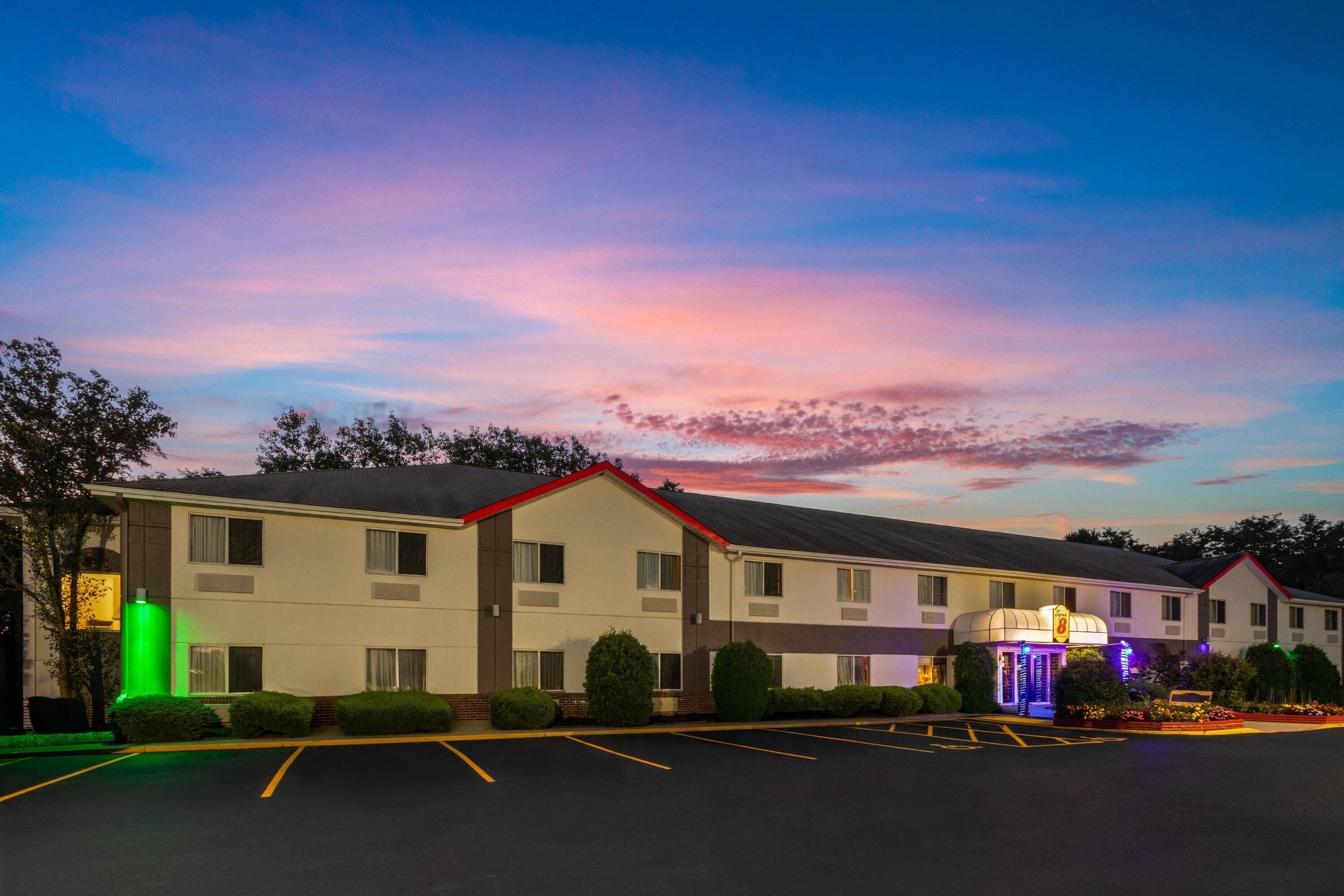 Un motel con estacionamiento y un edificio de techo rojo.
