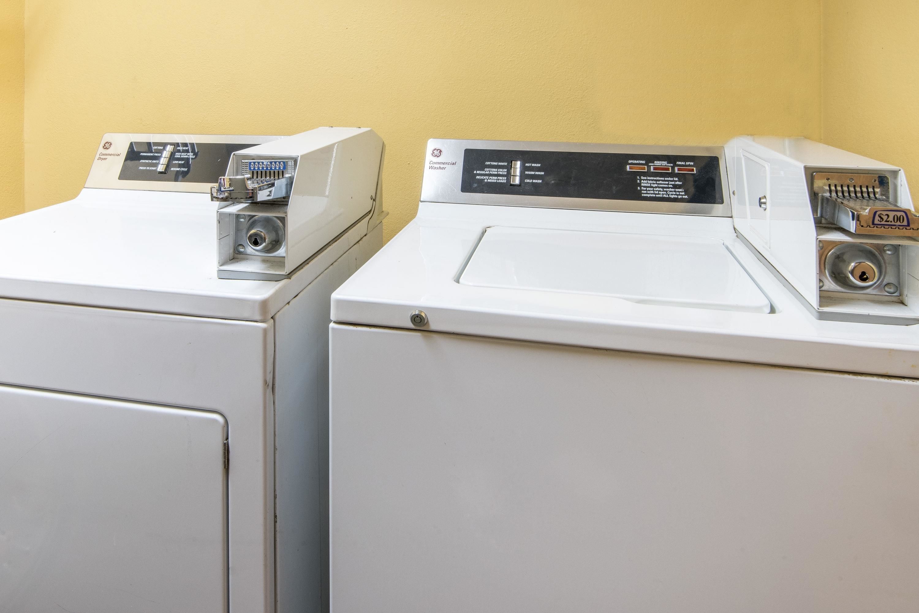 Two front-loading washing machines with control panels, set against a yellow wall.
