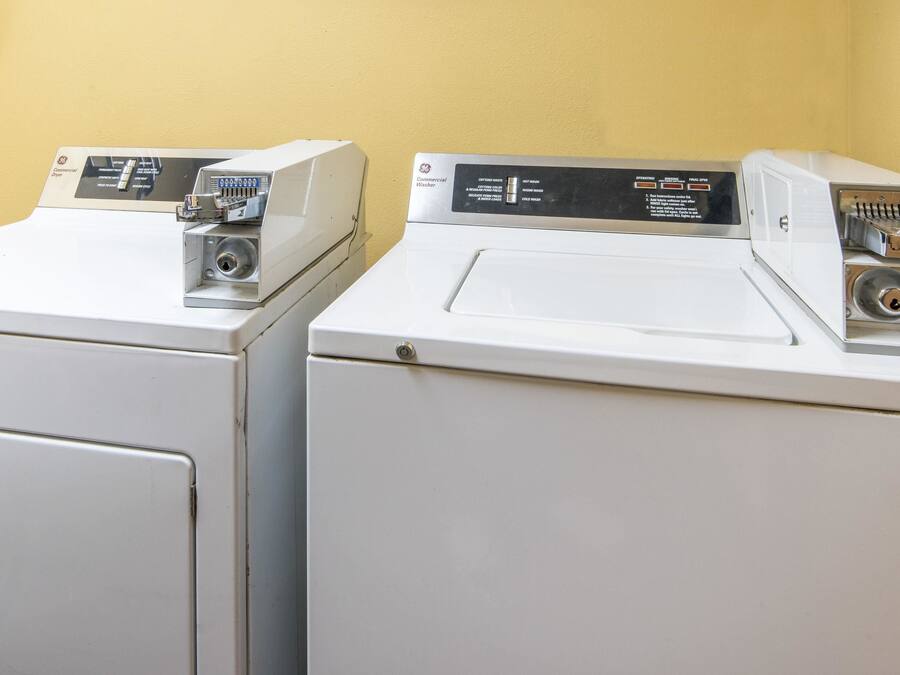 Two front-loading washing machines with control panels, set against a yellow wall.