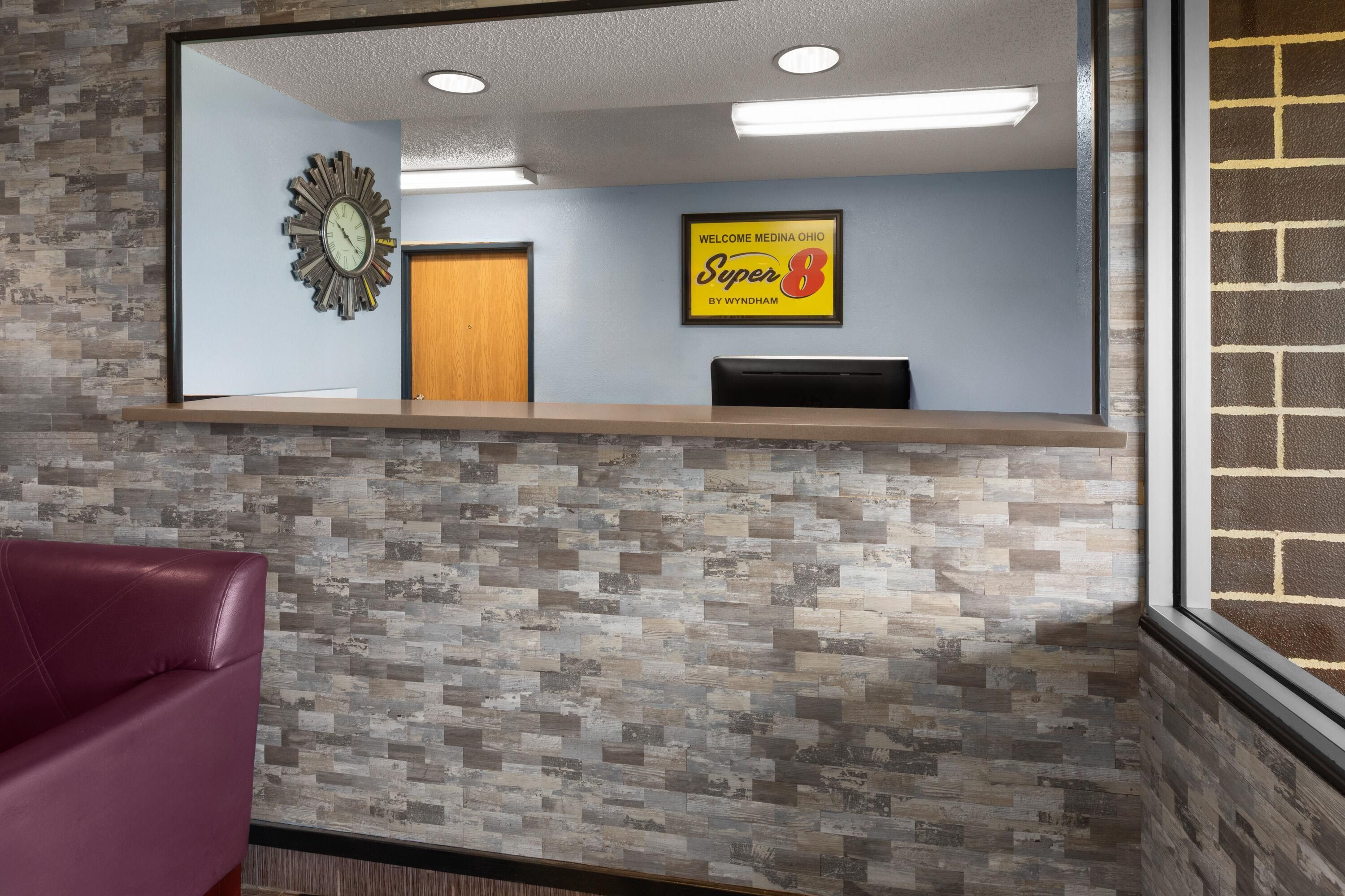 A reception area with a clock, a framed welcome sign, and a reception desk.