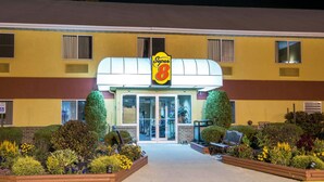 A Super 8 hotel with a yellow facade, large windows, and a well-maintained garden with various plants and flowers. - Super 8 by Wyndham Medina (Medina)