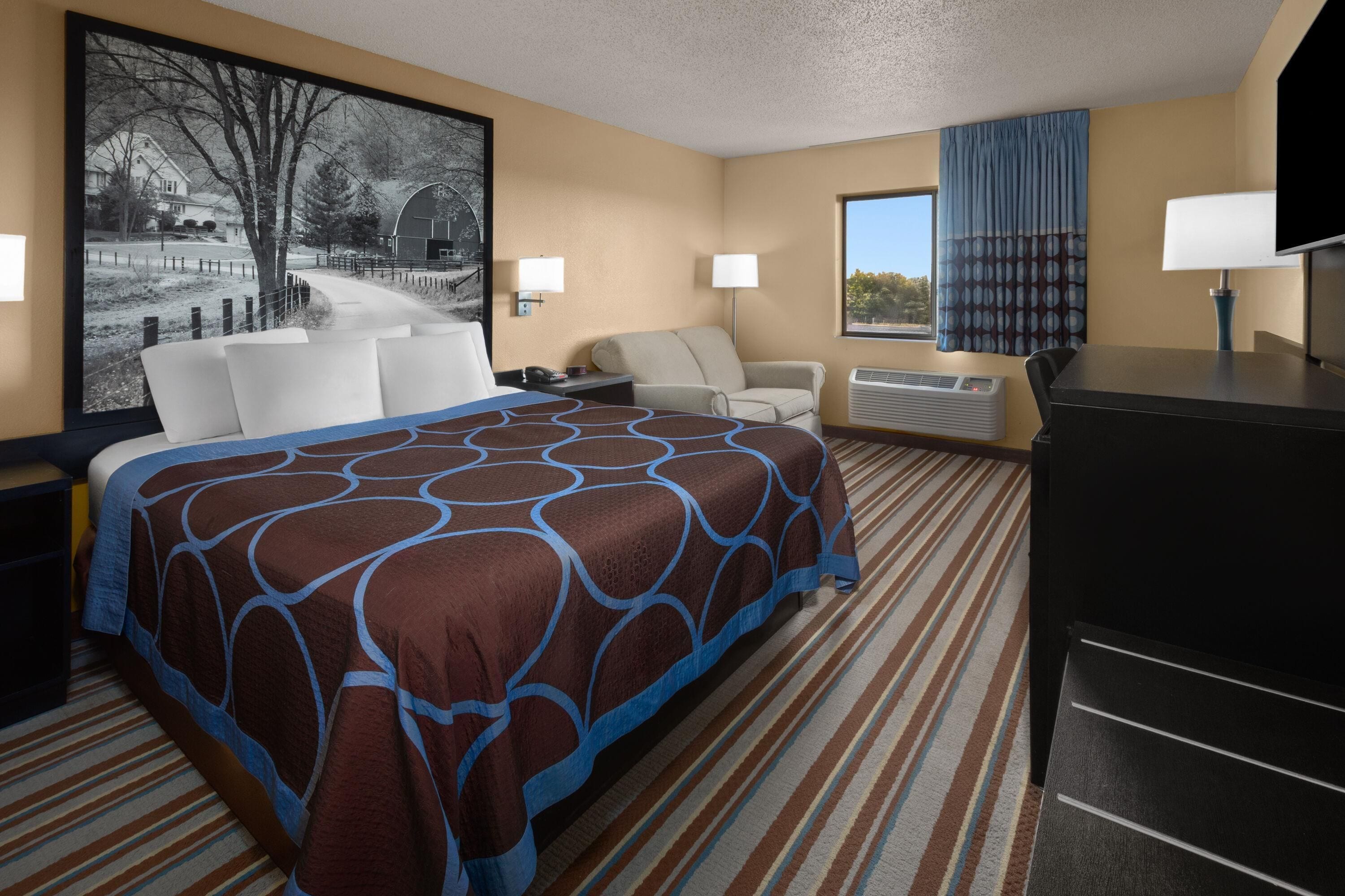 A hotel room with a bed, a desk, a chair, a television, and a window with curtains.
