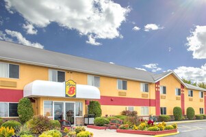 Un hotel con fachada amarilla, un letrero grande que dice "Super 8" y un estacionamiento con una bicicleta.