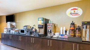 A breakfast bar with coffee machines, a microwave, and a coffee dispenser. - Super 8 by Wyndham Medina (Medina)