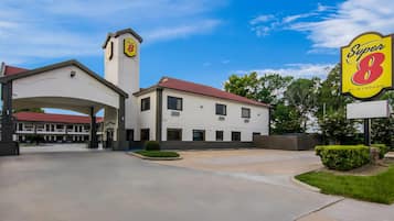A Super 8 motel with a central tower, a covered parking area, and a clear sky.