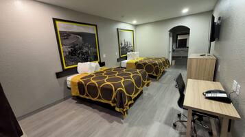 A hotel room with two beds, a desk, a chair, a telephone, and a television.