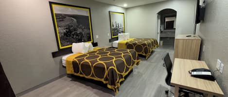 A hotel room with two beds, a desk, a chair, a telephone, and a television.