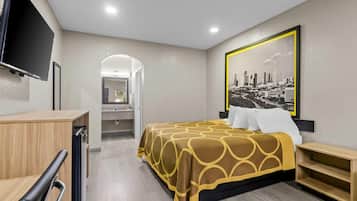 Ein Hotelzimmer mit einem Bett, einem Schreibtisch, einem Fernseher und einem Stadtbild.