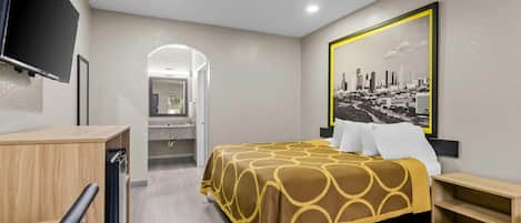 Quarto de hotel com cama, escrivaninha, televisão e pintura de paisagem urbana.