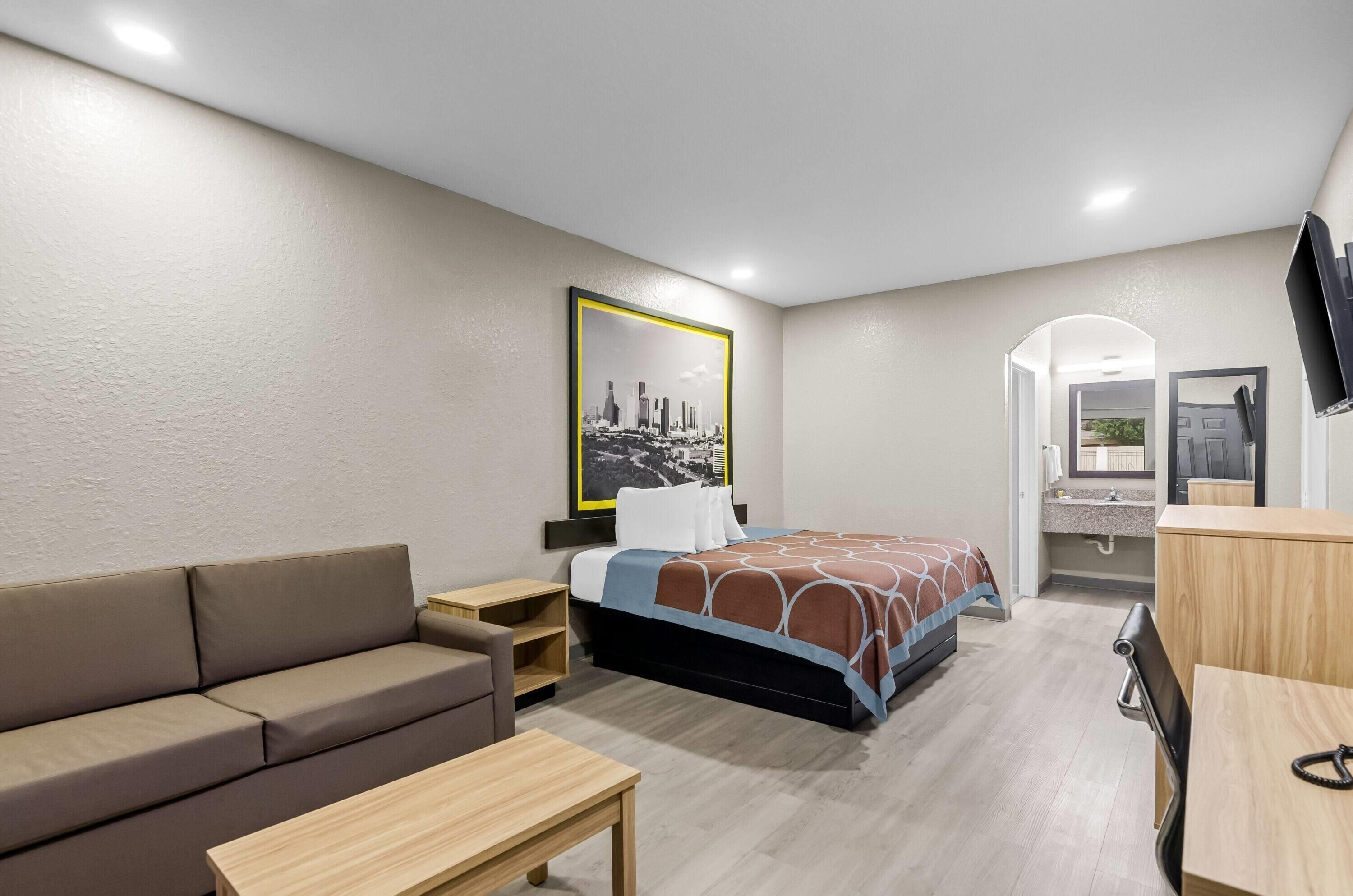 Una camera d'albergo con un letto, un divano, una scrivania e una televisione.