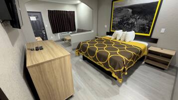 A modern hotel room with a bed, a desk, and a large window.