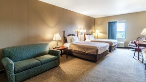 Ein Hotelzimmer mit einem grünen Sofa, zwei Betten, einem Schreibtisch und einem Fenster mit Vorhängen.