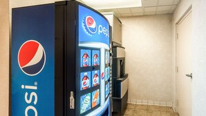 Ein Pepsi-Automaten in einer Halle mit Fliesenboden und einer Tür im Hintergrund.