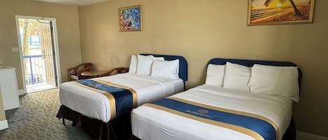 Une chambre d’hôtel avec deux lits, un bureau et une chaise. Une porte donne accès à un espace extérieur.