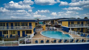 A hotel with a pool area, multiple balconies, and outdoor seating. - Sandals Inn (Daytona Beach)