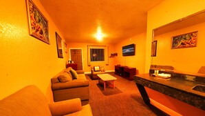 A living room with a sofa, a coffee table, and a TV. - Sandals Inn (Daytona Beach)