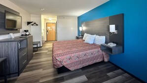 Een hotelkamer met een bed, een bureau met stoel, een televisie en een badkamer in de achtergrond.