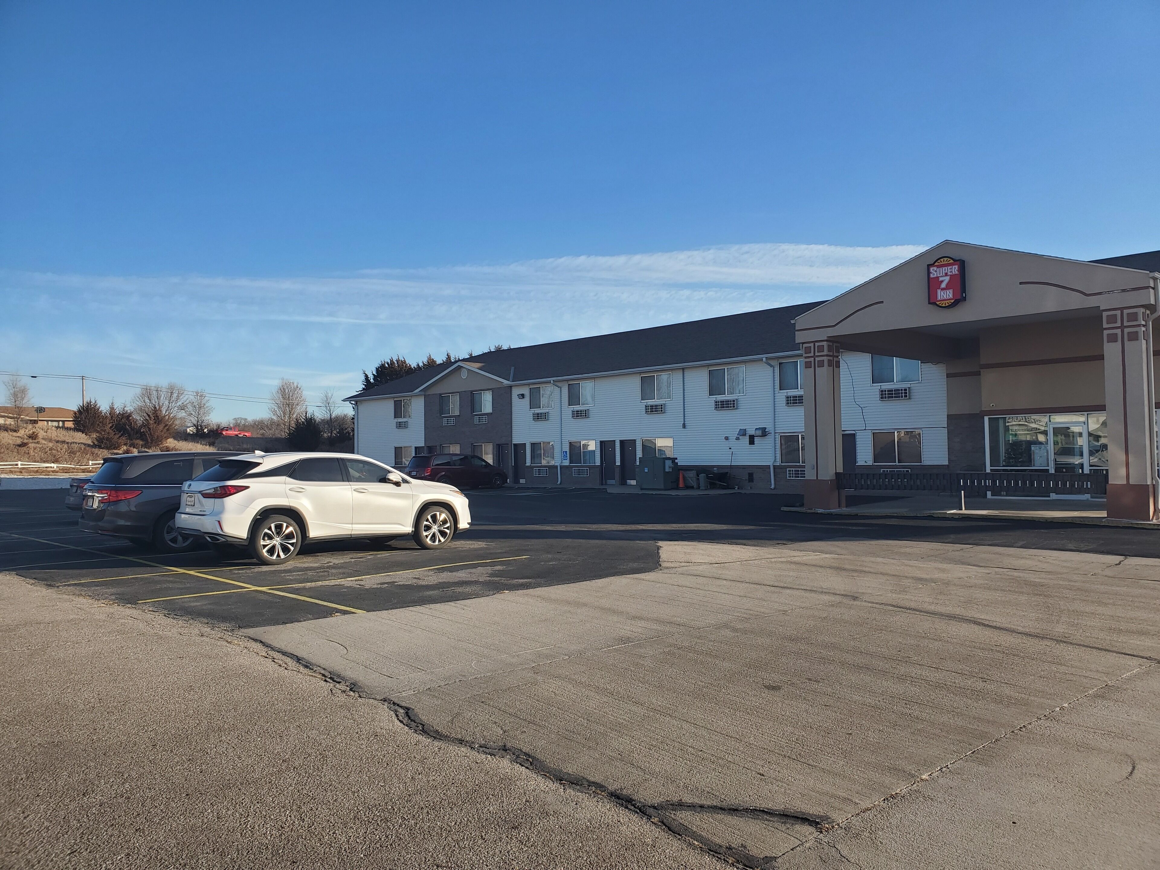 A Super 7 Inn with a parking lot and two parked cars.