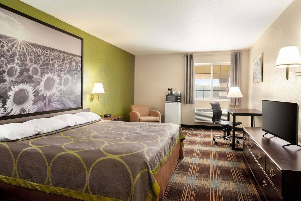 A hotel room with a bed, a desk, a chair, a television, and a large window.