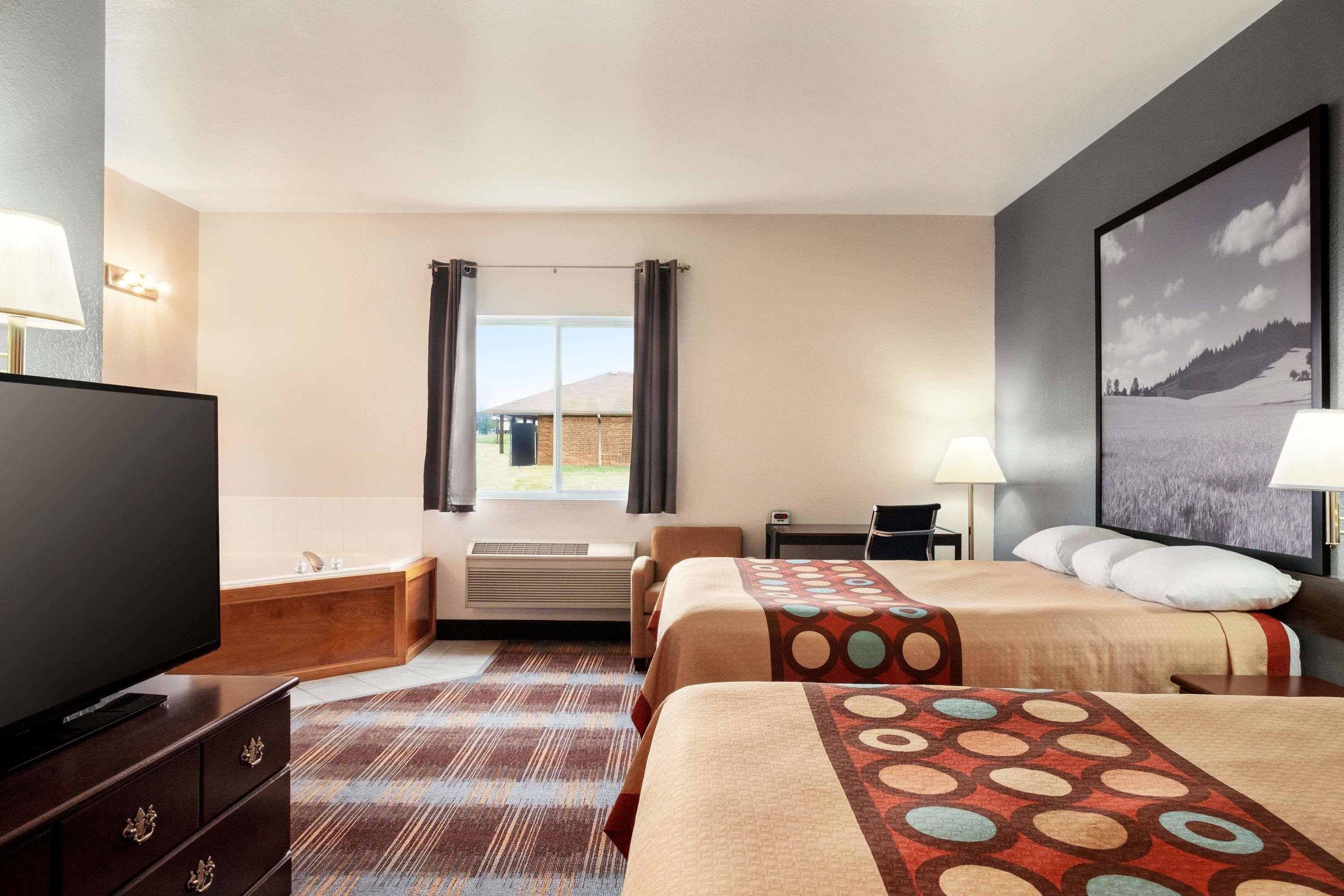 Una habitación de hotel con dos camas, televisión, escritorio y baño.