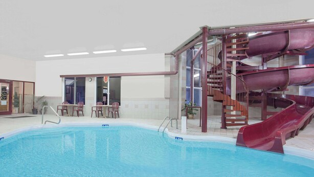 An indoor swimming pool with a water slide and seating area. - Super 8 by Wyndham Portage La Prairie MB (Portage La Prairie)