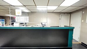 A reception desk with a computer and a phone, a bulletin board with notices, and a door to the right. - Rodeway Inn Dunmore (Scranton)