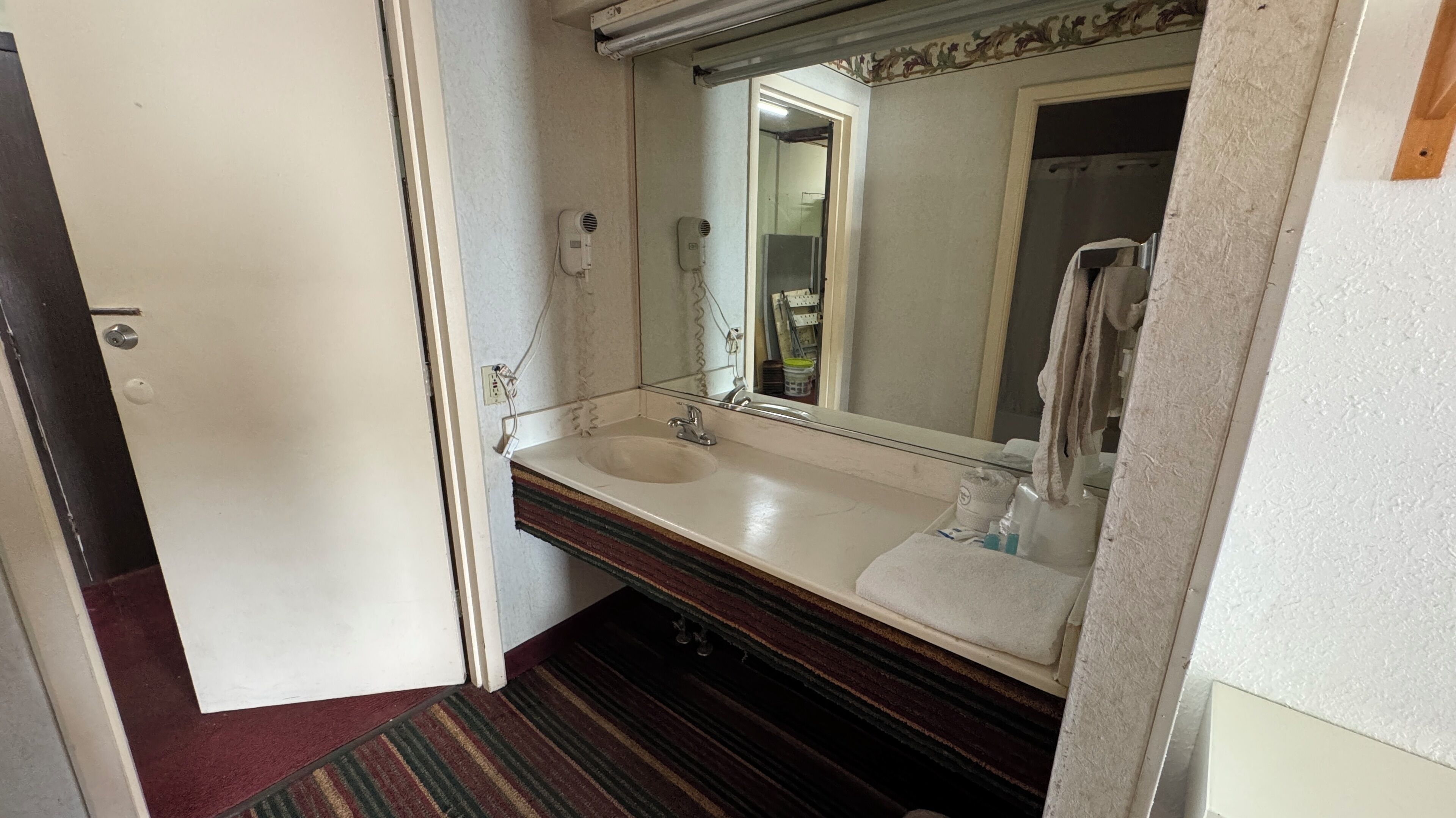 Un baño con lavamanos doble, espejo y toallero.