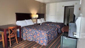 A hotel room with a bed, a desk, a chair, a television, and a refrigerator. - Rodeway Inn Dunmore (Scranton)