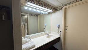 A bathroom with a large mirror, two hair dryers mounted on the wall, a sink, and a towel rack. - Rodeway Inn Dunmore (Scranton)