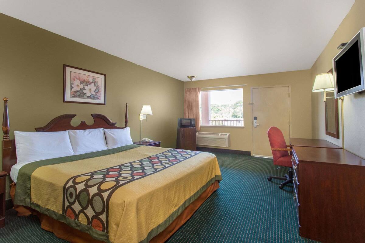 Ein Hotelzimmer mit Bett, Schreibtisch, Stuhl, Fernseher und einem Fenster mit Blick.