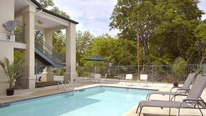 Une piscine avec des chaises longues, un espace salon couvert et un escalier menant à un niveau supérieur.