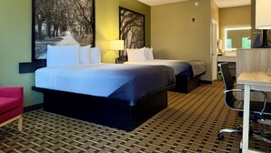 Une chambre d’hôtel avec deux lits, un bureau, une chaise et une grande fenêtre.