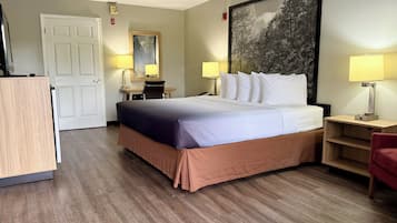 A hotel room with a bed, desk, chair, and two bedside lamps.
