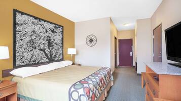 Une chambre d’hôtel avec un grand lit, une télévision, une commode et une horloge murale.